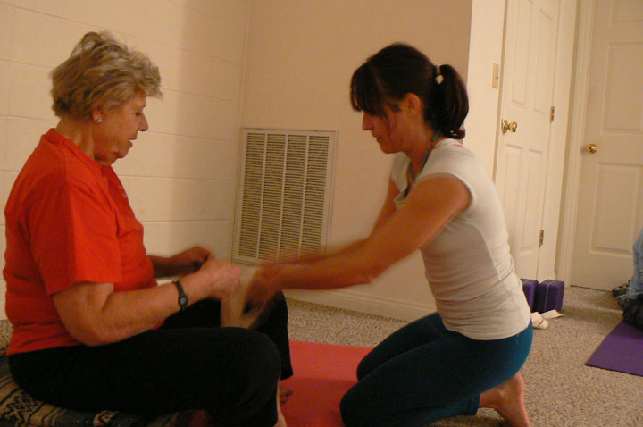 Nicole assists a student with an injured knee to aid in the execution of  yoga poses.